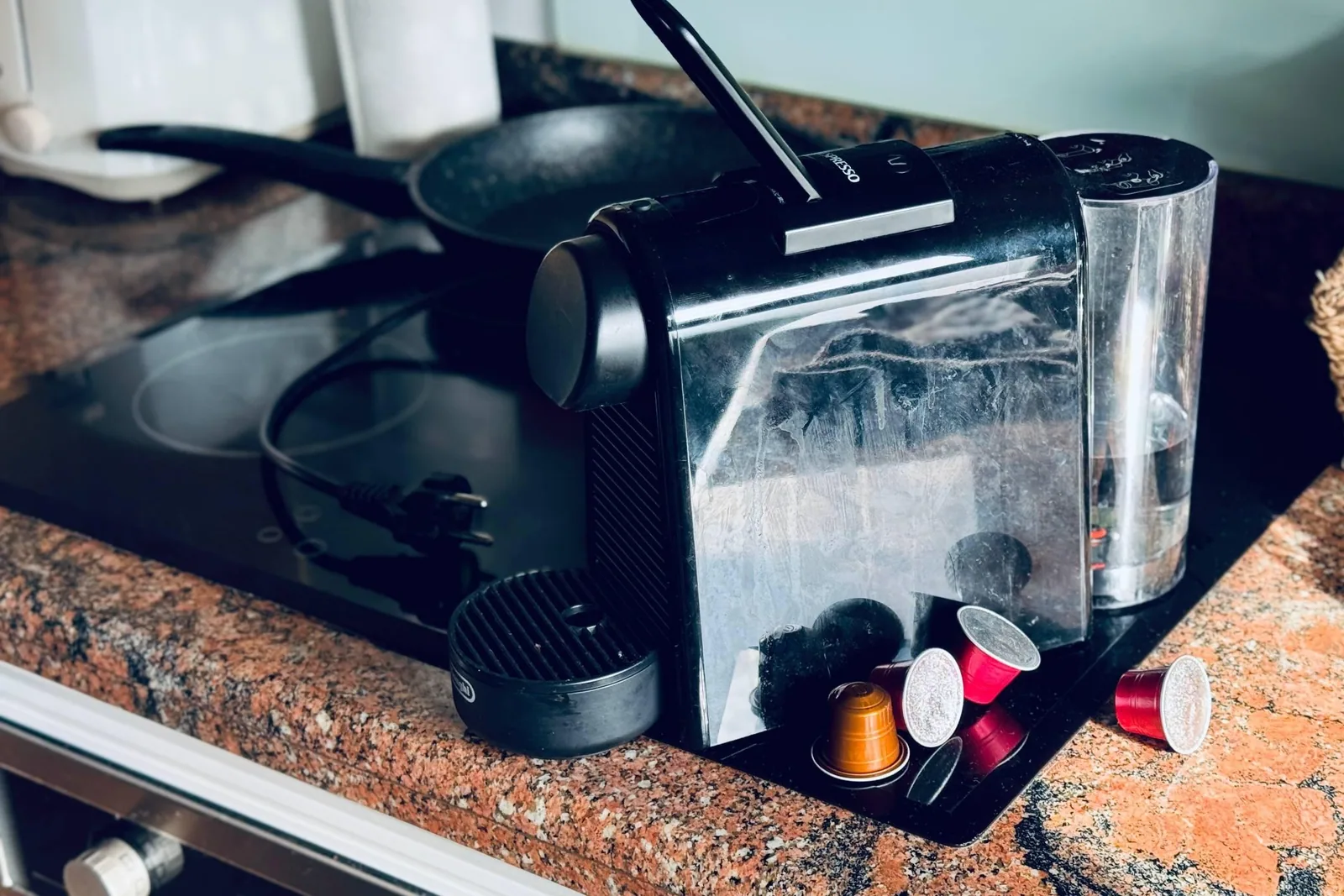 kapselmaskin på kjøkkenbenk med brukte Nespresso-kapsler